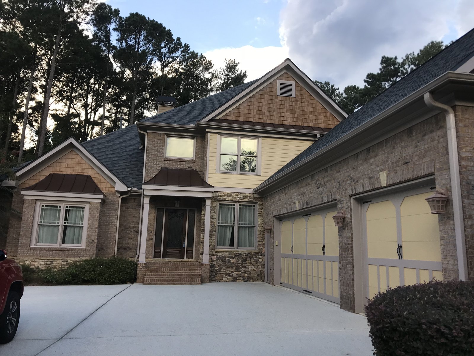 Tan carriage garage doors on a stone home Two tan carriage-style garage doors on a stone and brick two-story home