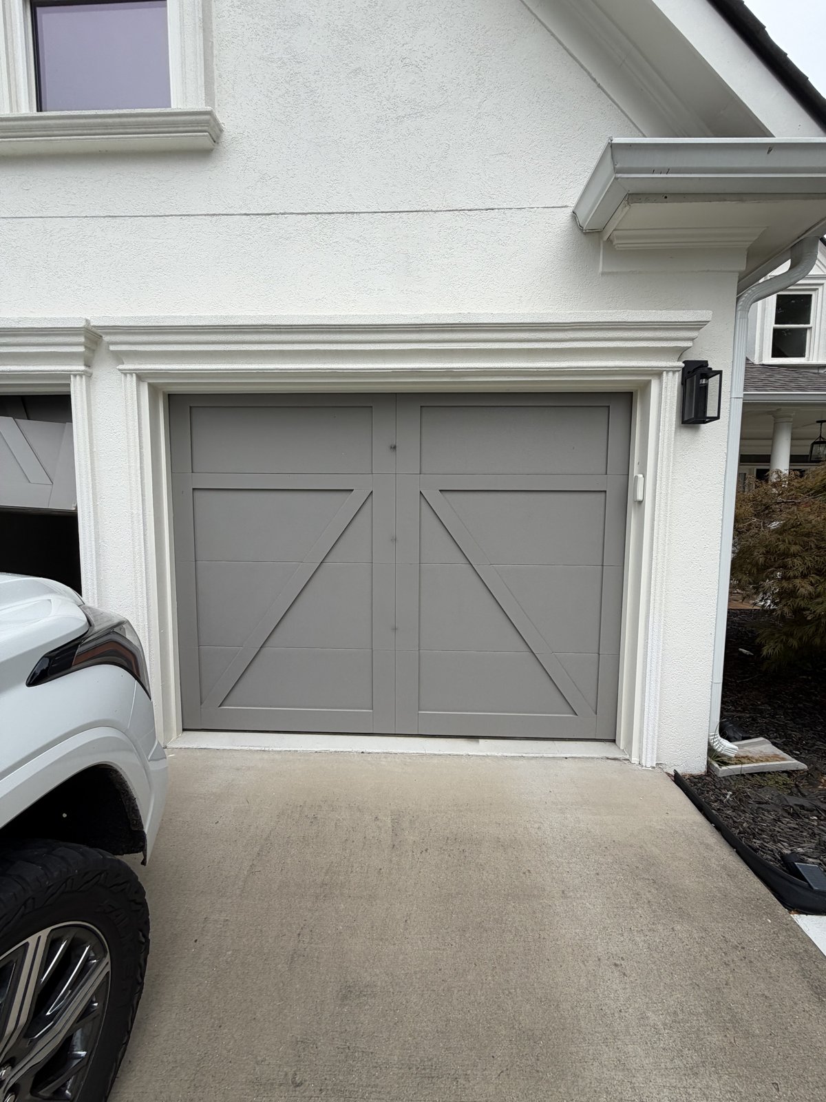 Gray crossbuck carriage garage door Gray single carriage garage door with crossbuck X panels on a white home