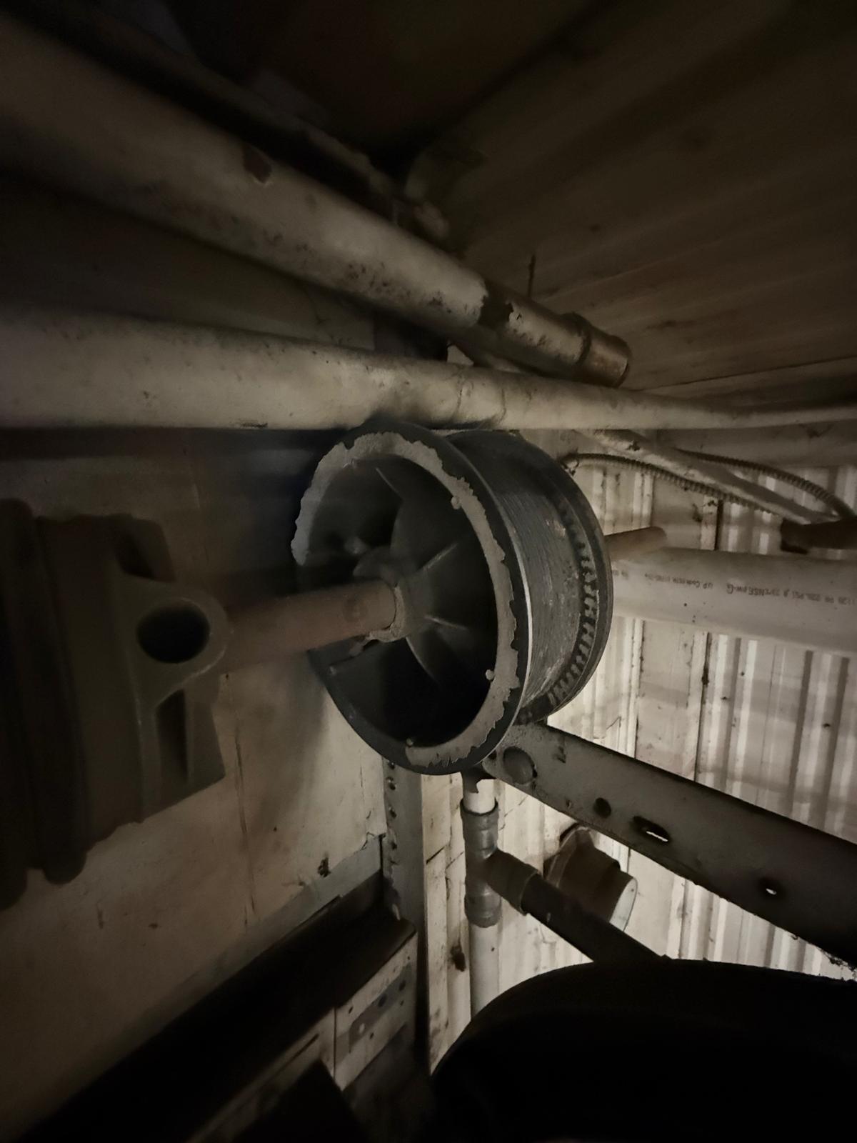 Garage door cable drum repair in Woodstock, GA Close-up of a garage door cable drum and torsion shaft during a cable repair in Woodstock, GA