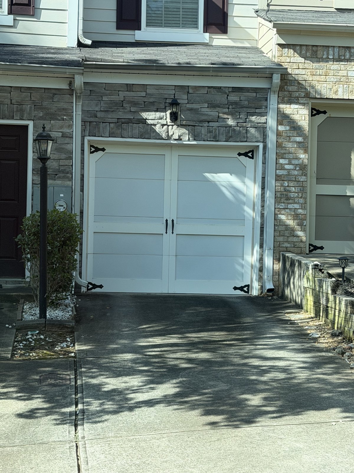 White carriage garage door on a townhome White carriage-style single garage door on a stone-front townhome