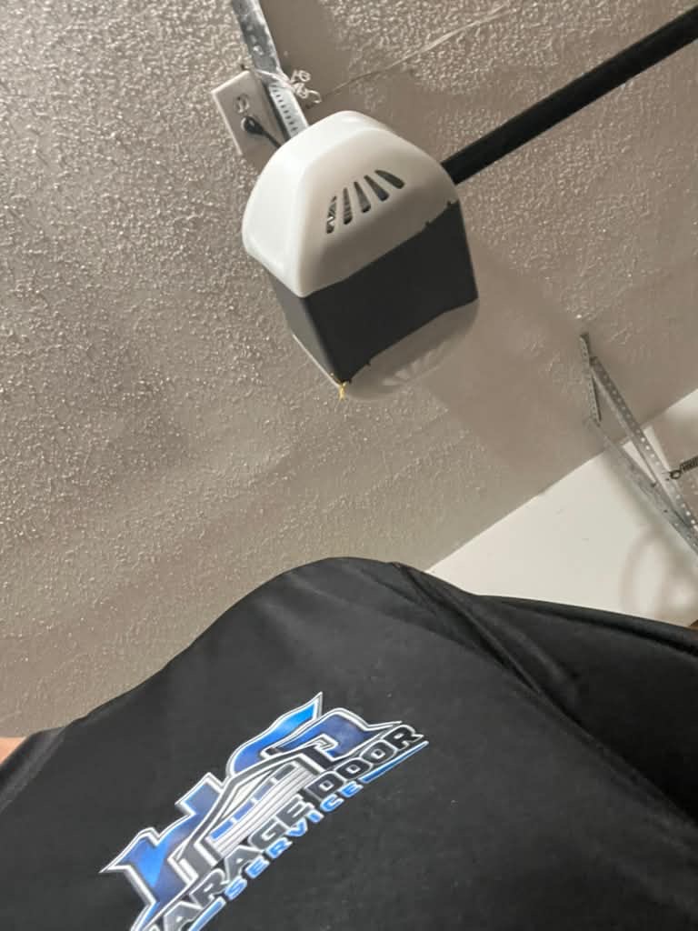 Garage door opener repair visit in Alpharetta, GA Technician from HG Garage Door Service checking a garage door opener mounted to the ceiling during a repair visit in Alpharetta, GA