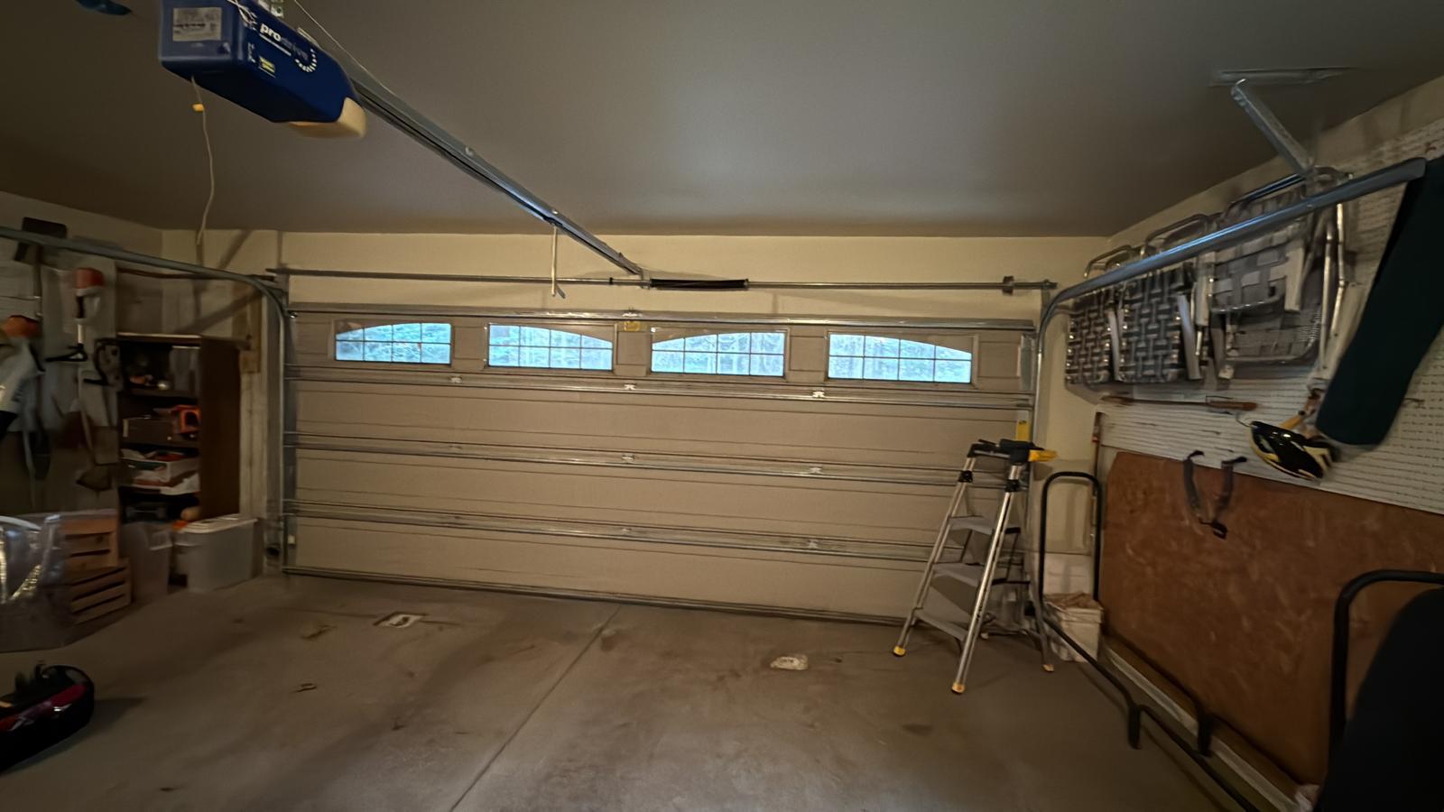 Garage door opener installation in Kennesaw, GA Newly installed chain-drive garage door opener above an insulated garage door with window panels in Kennesaw, GA