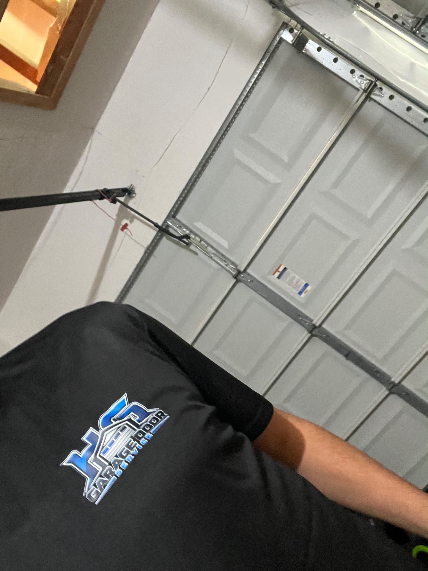 Garage door technician on a service call in Alpharetta, GA HG Garage Door Service technician working beside a sectional garage door and lift tracks during an Alpharetta, GA repair visit