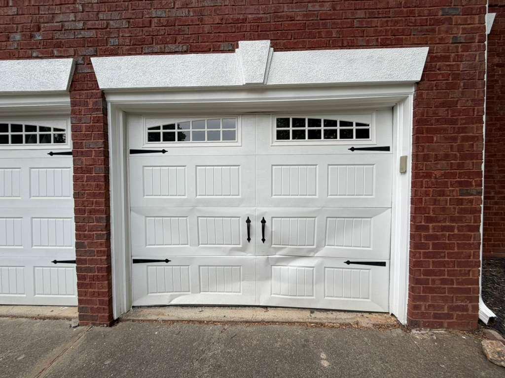 Dented garage door panel replacement in Roswell, GA Carriage-style garage door with bowed and dented lower panels awaiting panel replacement in Roswell, GA