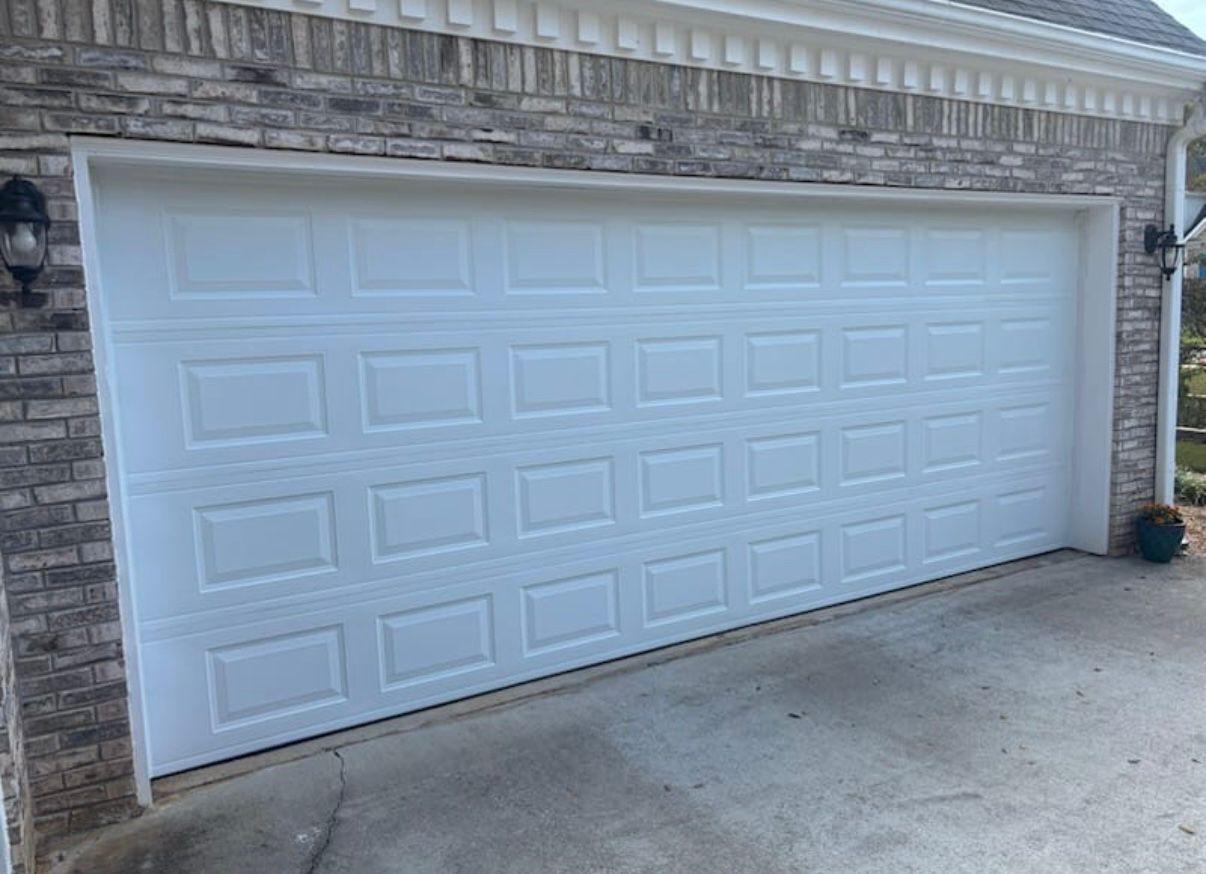 New double garage door installation in Roswell, GA New white raised-panel double garage door installed on a light brick home in Roswell, GA