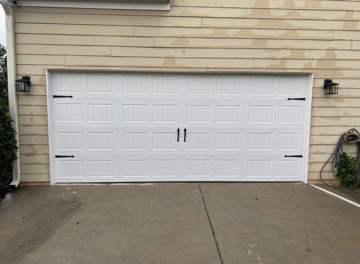Carriage-style garage door installation in Woodstock, GA White carriage-house style garage door with black hinges and handles installed in Woodstock, GA