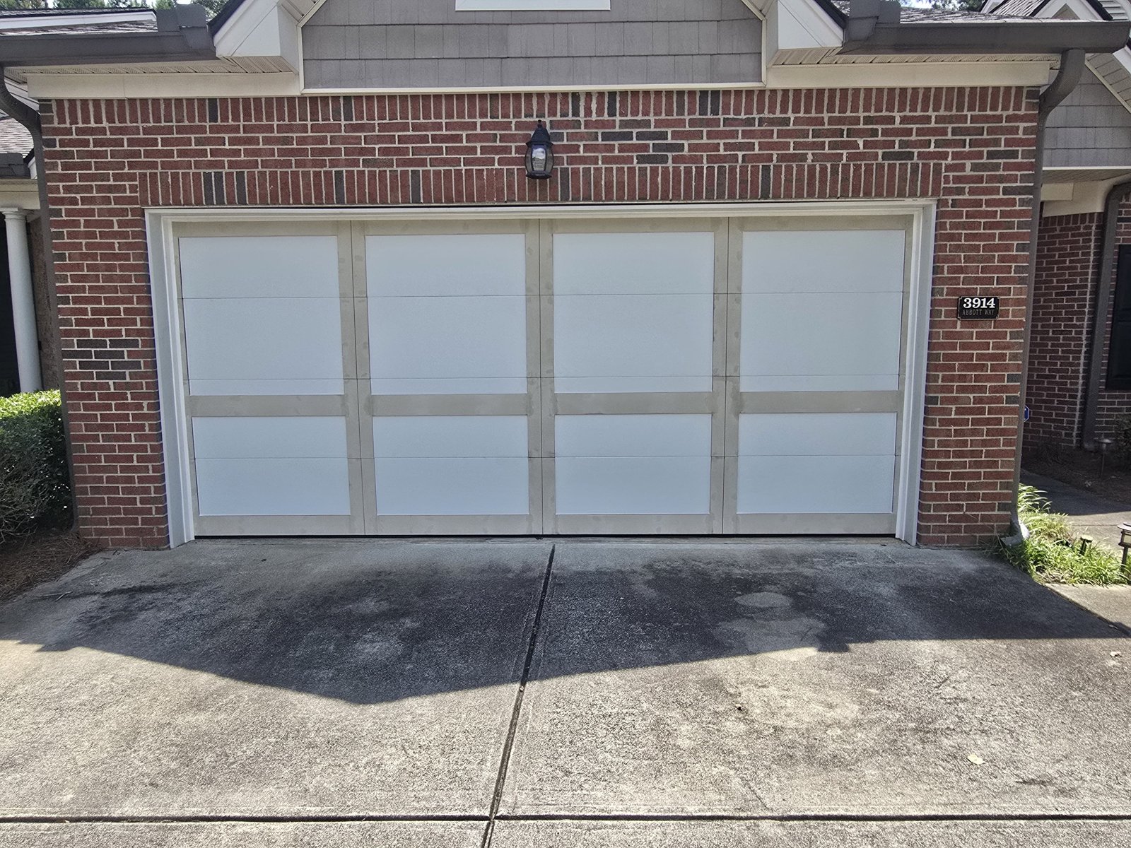 Carriage-style double garage door on a brick home Tan and white carriage-style double garage door on a red brick home