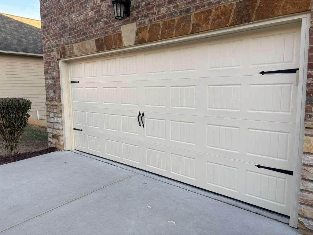 Carriage-house garage door installation in Alpharetta, GA Almond carriage-house style garage door with black decorative hardware installed in Alpharetta, GA