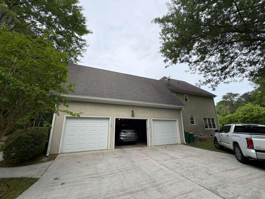 Three-car garage door replacement in Ball Ground, GA Three-bay garage with new white garage doors installed on a stucco home in Ball Ground, GA